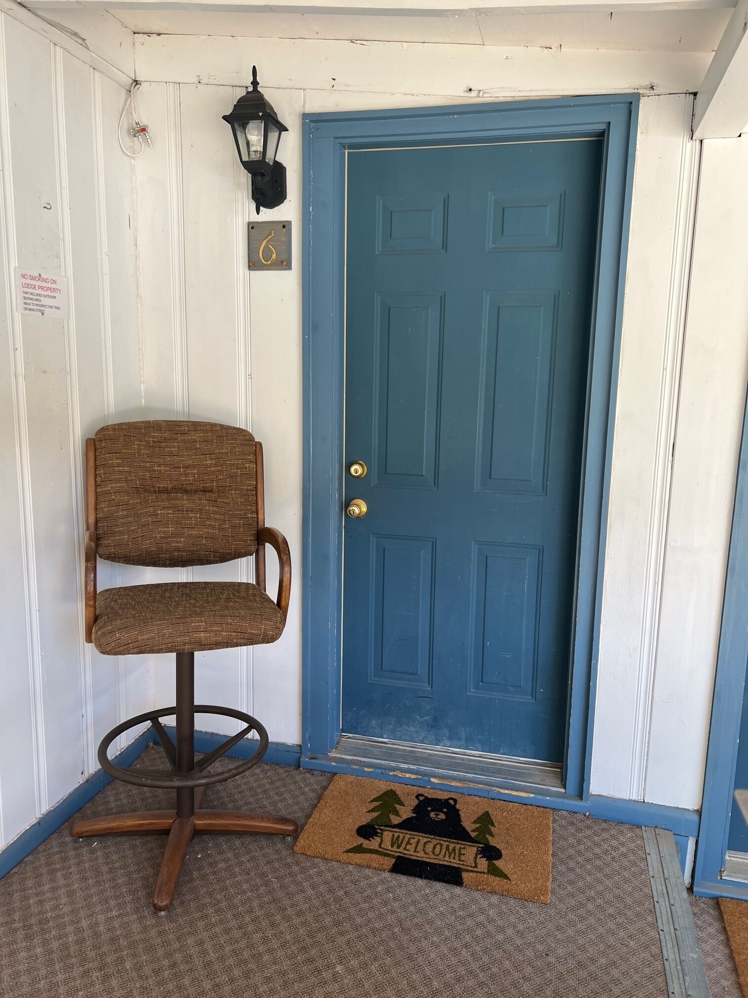 A blue door with a doormat that reads "WELCOME" and a bear design.