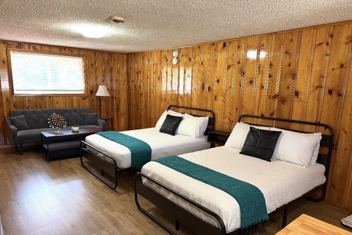 Una habitación con dos camas, un sofá y una mesita.