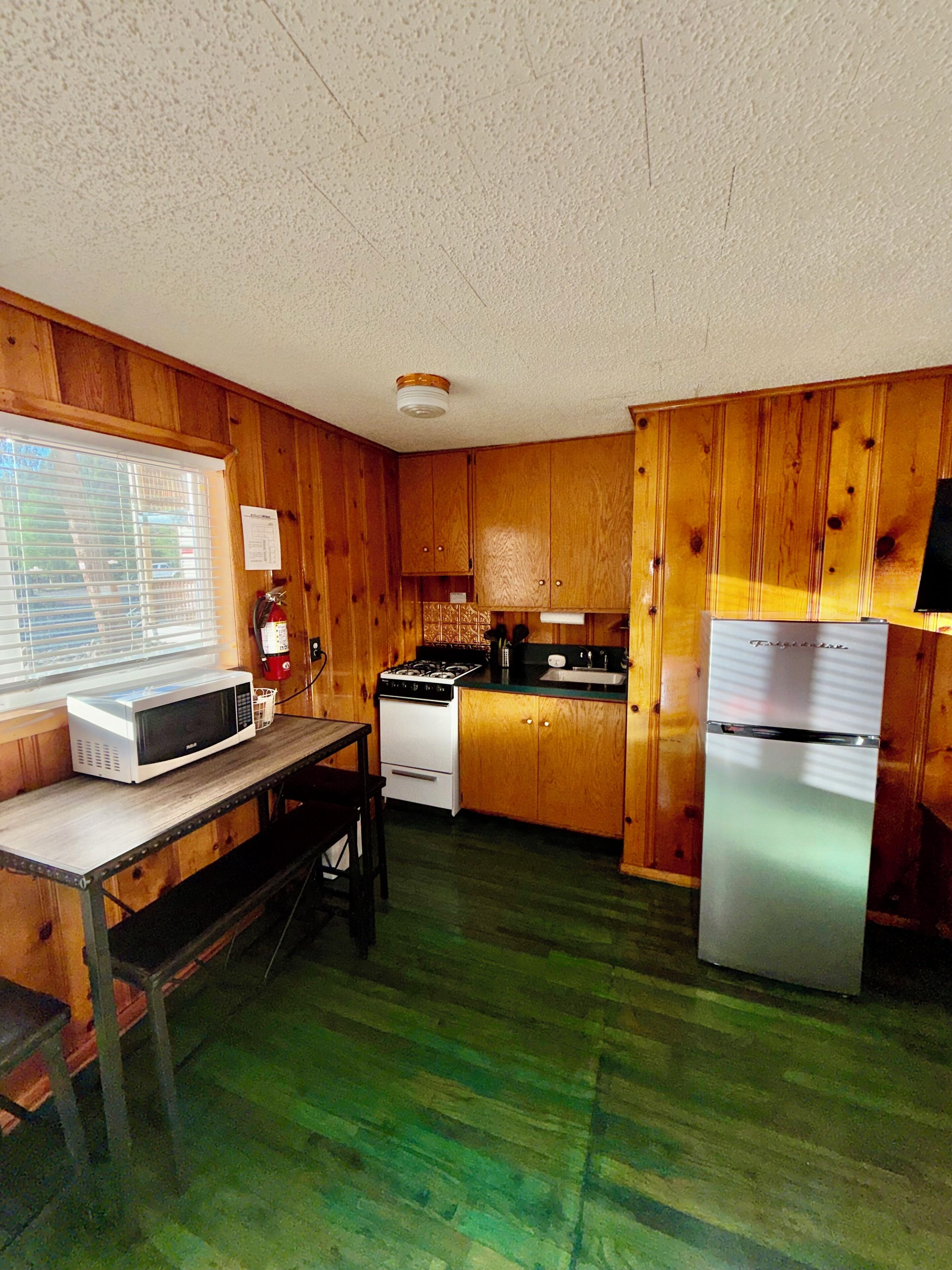 A compact kitchen with wooden cabinets, a microwave, stove, and refrigerator.