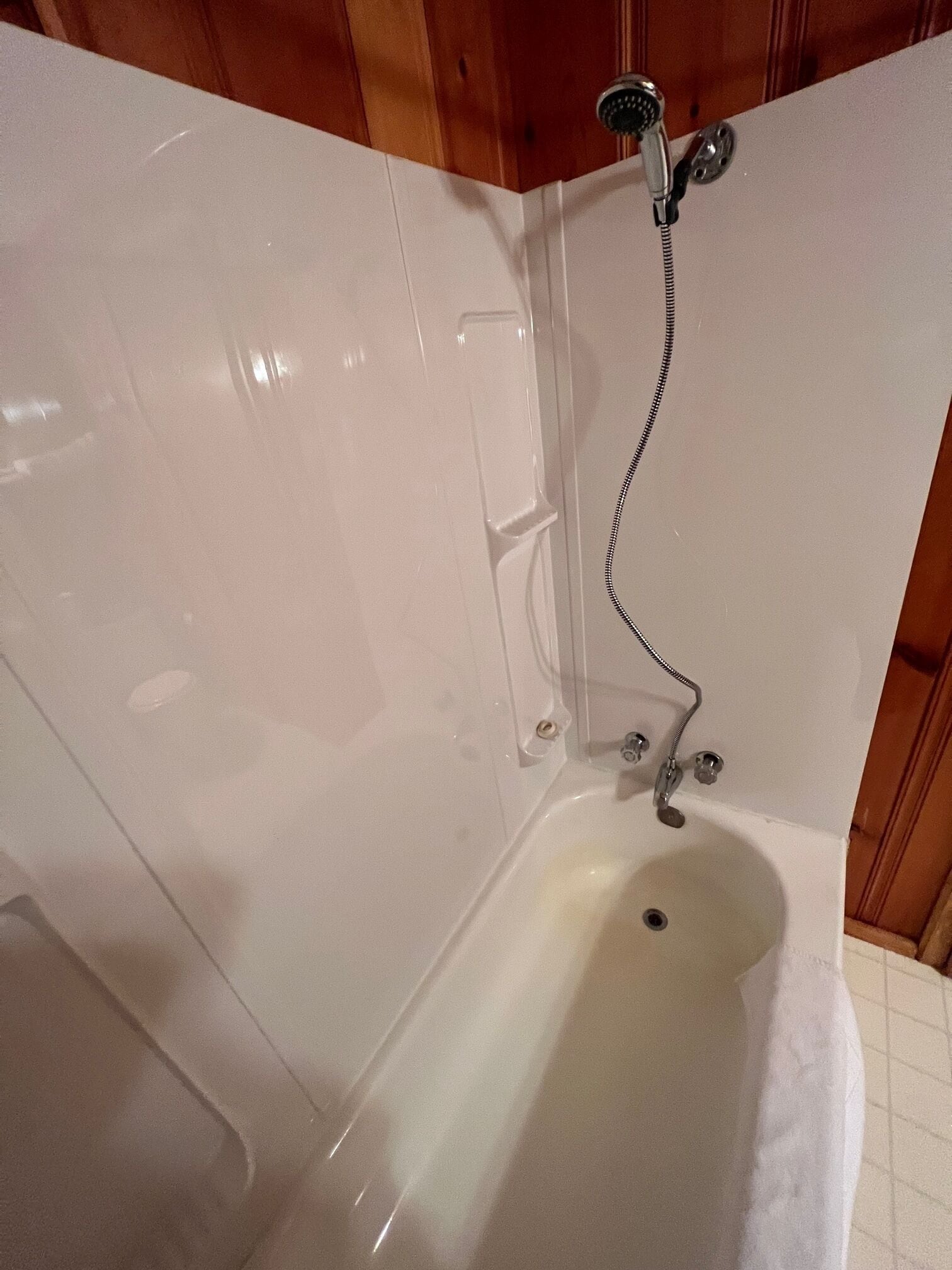 A bathtub with a showerhead, a towel rack, and a drain.