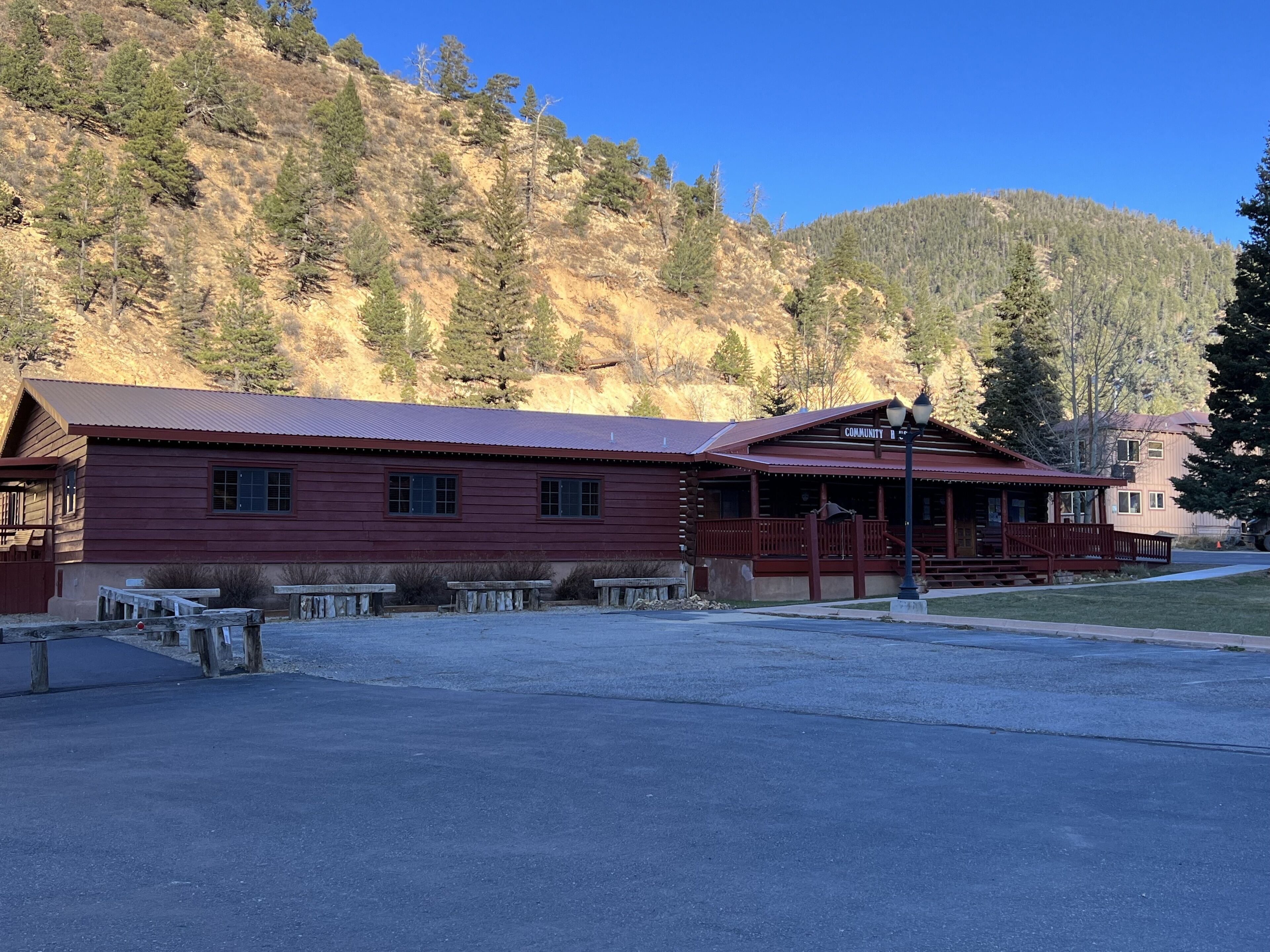 A lodge with a red exterior, a porch, and a parking area in front.