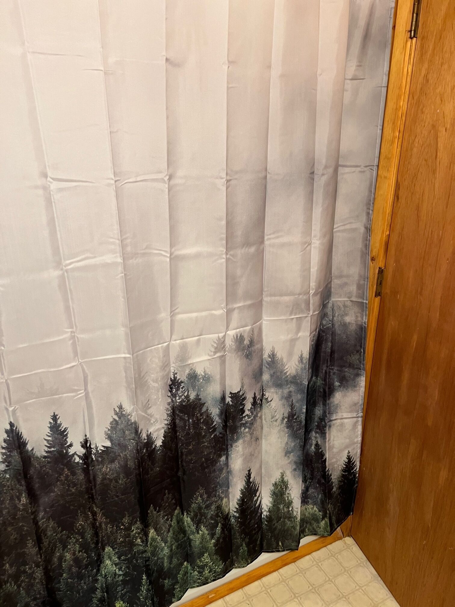 Een kamer met een gordijn waarop een boslandschap is afgebeeld.