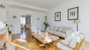 A spacious living room with a herringbone floor, a sofa, a coffee table with flowers, and a fireplace. - Superbe appart de 129m2, 3 ch-Neuilly 2 min Paris (Neuilly-sur-Seine)