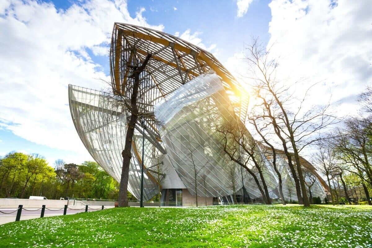 Een modern architecturaal gebouw met een uniek, hoekig ontwerp, omringd door een gazon met bomen.