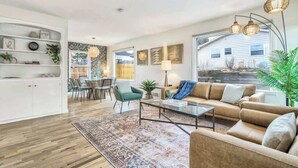 Uma sala de estar moderna com sofá, mesa de centro e área de jantar com cadeiras e mesa.