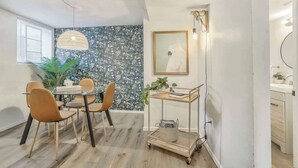A dining area with a round table, four chairs, a pendant light, a wall-mounted picture, and a cart with a plant. - El Sereno Bungalow! Pet-Friendly Ivywild Flat (Colorado Springs)