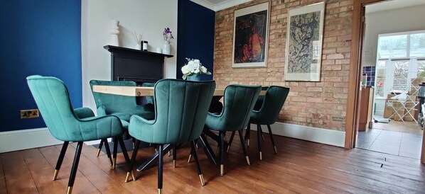 Un comedor con pared de ladrillo, chimenea y una mesa con sillas.