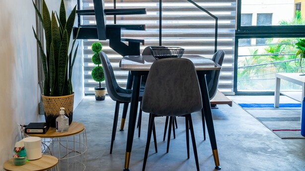 A modern dining area with a staircase, a potted plant, and a view of the outside. - New Loft NYC style, King Bed, High Speed Wifi, (Santo Domingo)