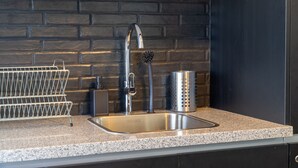A kitchen with a stainless steel sink, a modern faucet, and a metal colander on the countertop. - New Loft NYC style, King Bed, High Speed Wifi, (Santo Domingo)