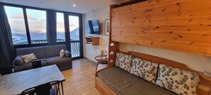 Ein gemütliches Zimmer mit einer Couch, einem kleinen Tisch und einem Fernseher.