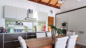 Une cuisine moderne avec des meubles blancs, une table à manger en bois et une grande fenêtre.