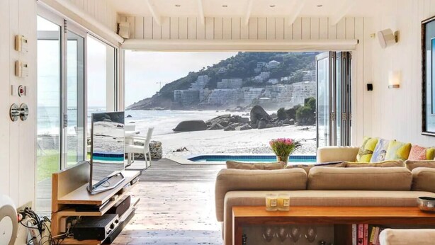 Un vaste espace de vie avec une grande fenêtre donnant sur une plage et une piscine.