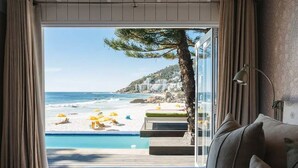 Une chambre avec un grand lit, une vue sur la plage et une piscine.