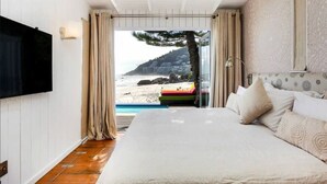 Une chambre avec un grand lit, un téléviseur fixé au mur et une vue sur la plage.