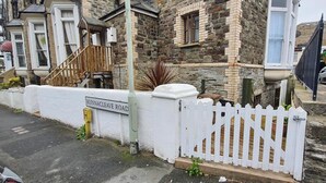 A residential street with stone houses, a white picket fence, and a sign for 'Runnacleave Road'. - Cosy Apartment Close to Tunnels Beaches (Ilfracombe)