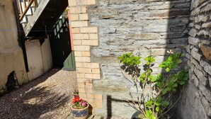 A courtyard with a stone wall, a wooden staircase, and potted plants. - Cosy Apartment Close to Tunnels Beaches (Ilfracombe)