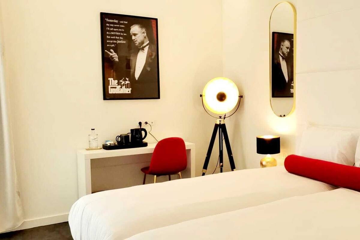 Ein Hotelzimmer mit einem großen Bett, einem Schreibtisch mit Stuhl, einem Spiegel und einem Bild an der Wand.