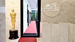 Eine Hotelhalle mit einem Marmor-Rezeptionsschalter, einem roten Teppich und einer Oscar-Statuette.