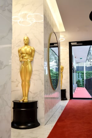 A marble wall with a gold statue of a figure, a large mirror, and a red carpet leading to a door. - Lisbon City Hollywood Hotel (Lisbon)