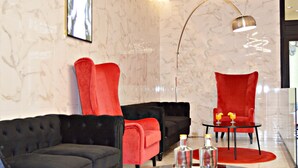 Ein modernes Wohnzimmer mit einem schwarzen Sofa, roten Sesseln und einem Glastisch.