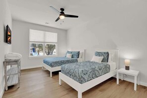 A bedroom with two beds, a ceiling fan, a window, and a bedside table with a lamp. - Lake-Pool-Beach-Gym-Boat Access (Lago Vista)