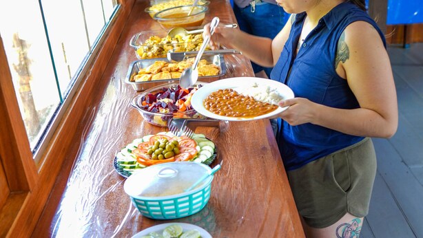 Una mesa de buffet con diversos platos, incluyendo una ensalada de piña y un plato de frijoles.