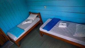 Dos camas literas de madera con sábanas blancas y toallas azules, en una habitación con paredes azules y suelo de madera.