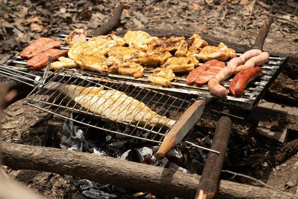 A grill with various meats and vegetables being cooked over an open fire.