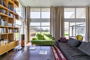 A modern living room with a green sofa, a grey couch, and a bookshelf filled with books. - Bains de Lumière - Belle Maison Contemporaine (Moëlan-sur-Mer)