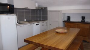 A compact kitchen with white cabinets, a microwave, a dishwasher, and a wooden table with a woven basket.