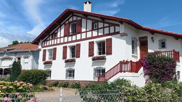 A traditional half-timbered house with a red staircase, multiple windows with shutters, and flower boxes.