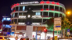 Un hotel de varios pisos con señalización iluminada que dice "Zoom Hotel".