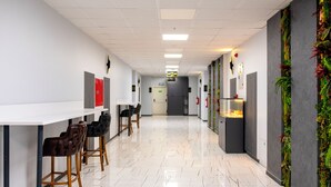 Un pasillo moderno con piso de mármol blanco, taburetes de bar y una larga barra.