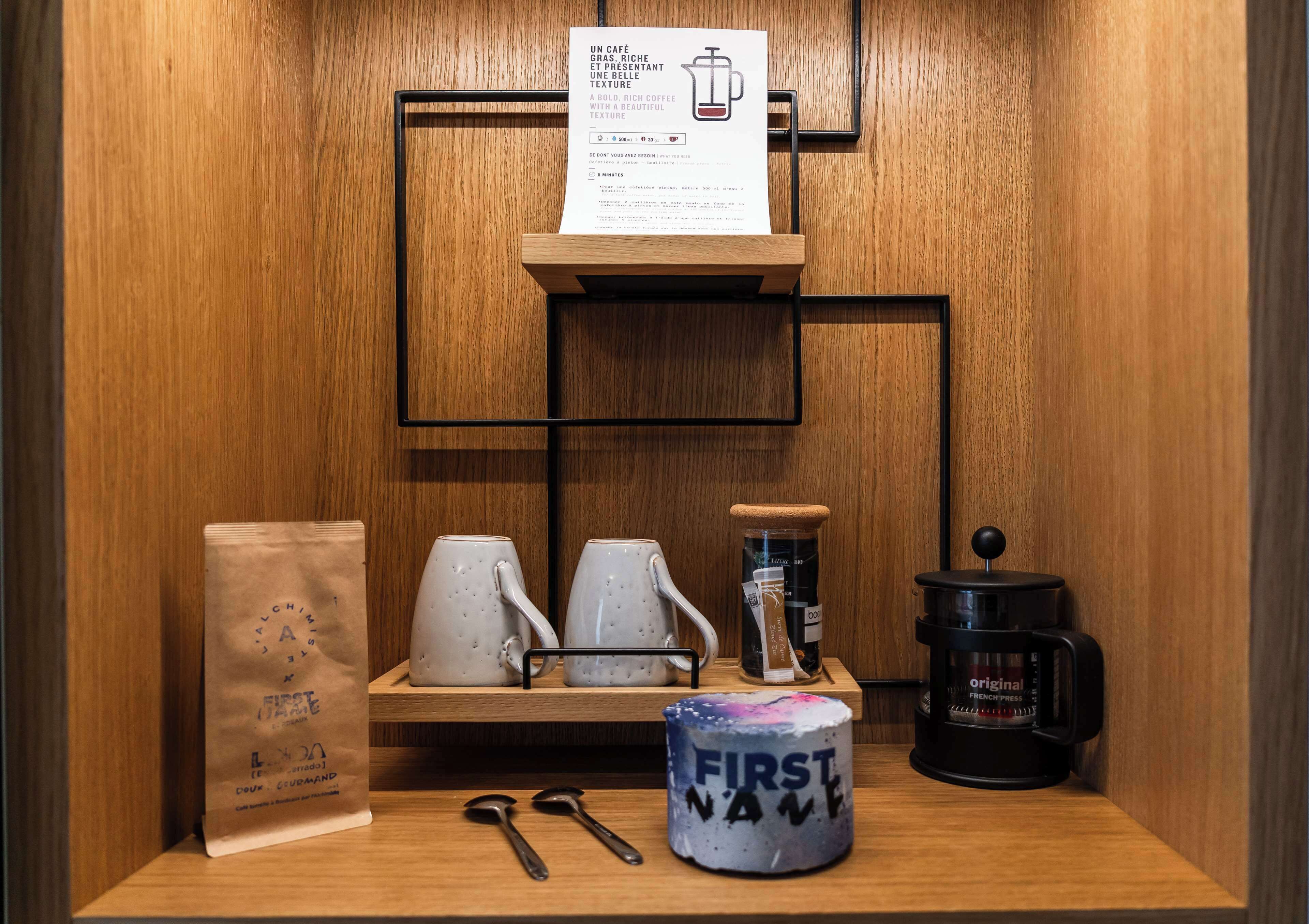 Una estación de café con un molinillo, una prensa francesa y una taza con el nombre 