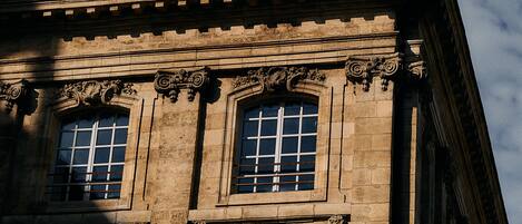 Un edificio histórico con intrincados detalles de piedra, ventanas amplias y un balcón con barandilla.