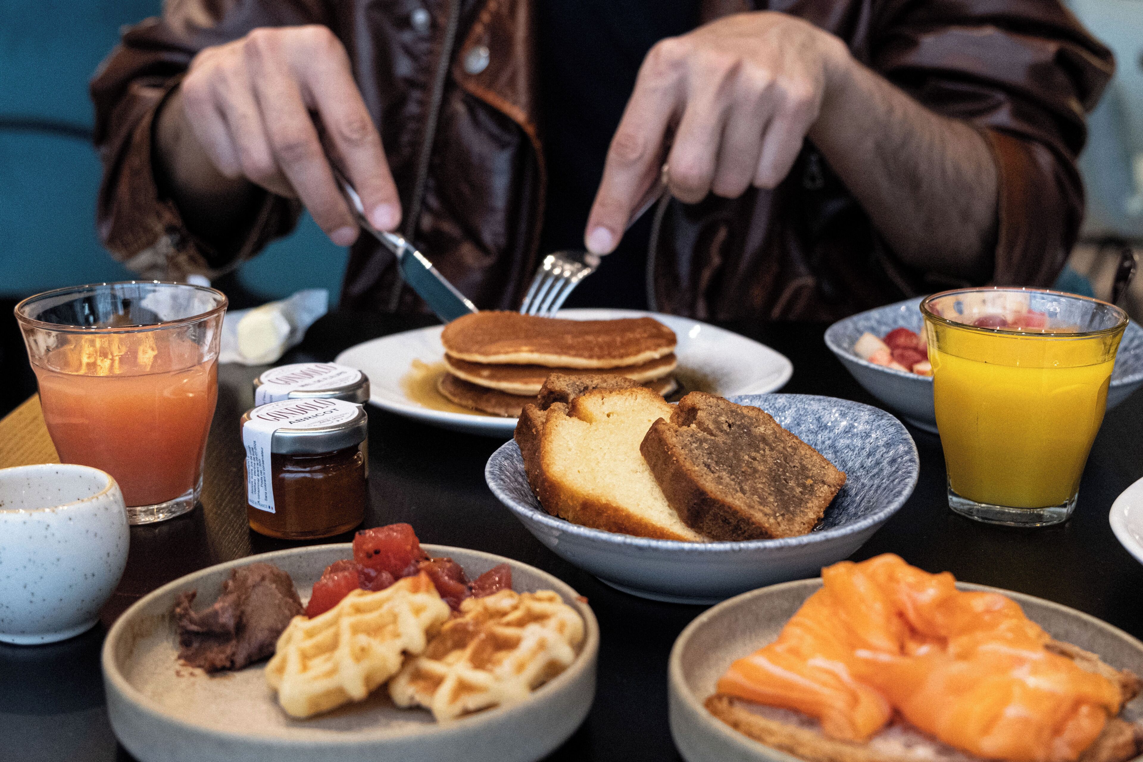 Een ontbijttafel met pannenkoeken, toast, wafels en zalm.