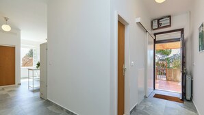 A hallway with a wooden door, a white wall, and a tiled floor. - Hedera Estate, Hedera A30 (Dubrovnik)