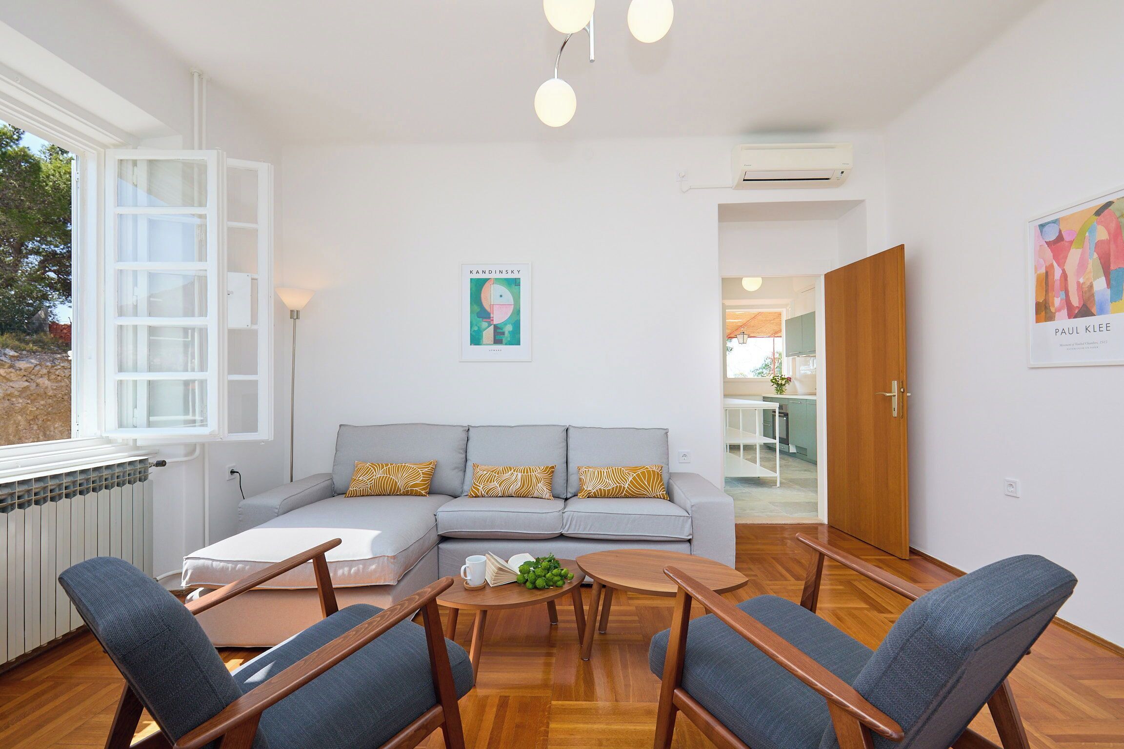 A modern living room with a grey sofa, wooden coffee table, and blue chairs.