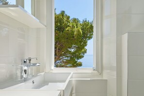 Une salle de bain moderne avec une grande fenêtre, un lavabo blanc et un robinet chromé.