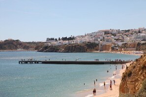 Une ville côtière dotée d’une plage, d’une jetée et de bâtiments construits sur une colline.