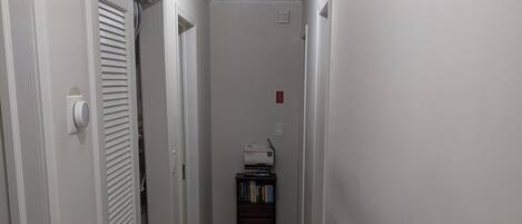 A narrow hallway with wooden flooring, white walls, and a ceiling light fixture.