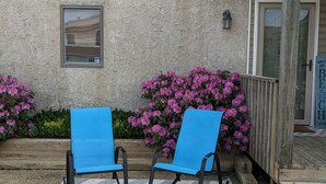 Ein Gebäude mit einer beigen Fassade, einer Veranda mit zwei blauen Schaukelstühlen und pinkfarbenen Blumen im Hintergrund.
