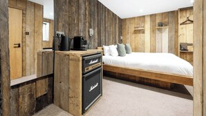 A bedroom with a wooden wall panel design, a bed with white bedding, and a Marshall amplifier on a dresser. - The Retreat, Windermere (windermere)