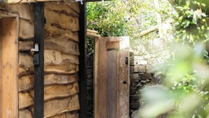 A rustic wooden door leading to a stone wall, with a wooden structure on the left and greenery in the background. - The Retreat, Windermere (windermere)