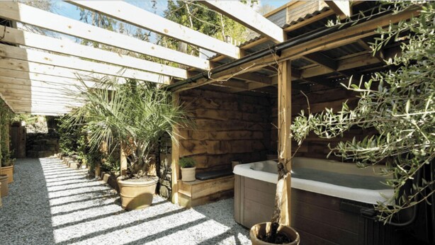 A spa area with a hot tub, wooden pergola, and potted plants. - The Retreat, Windermere (windermere)
