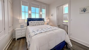Een slaapkamer met een groot bed, twee nachtkastjes, een plafondventilator en een raam met uitzicht.