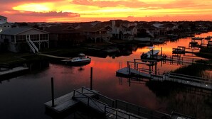 A marina with docked boats, a small boat on the water, and houses in the background. - On canal. 3 minute walk from beach! 5 minutes from everything!! (Ocean Isle Beach)
