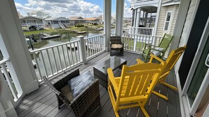 A covered balcony with wicker furniture and a view of a marina. - On canal. 3 minute walk from beach! 5 minutes from everything!! (Ocean Isle Beach)