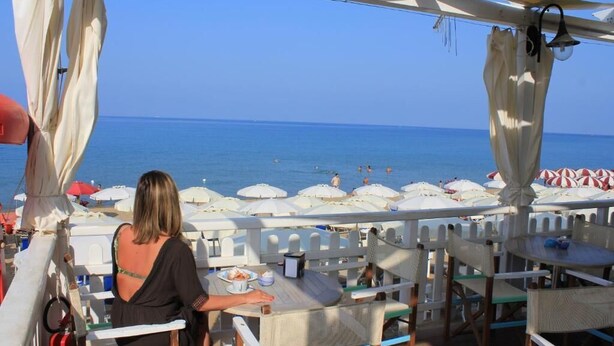 A beachside restaurant with outdoor seating overlooking the sea, featuring white umbrellas and wicker furniture. - Hotel Maria (Castellabate)