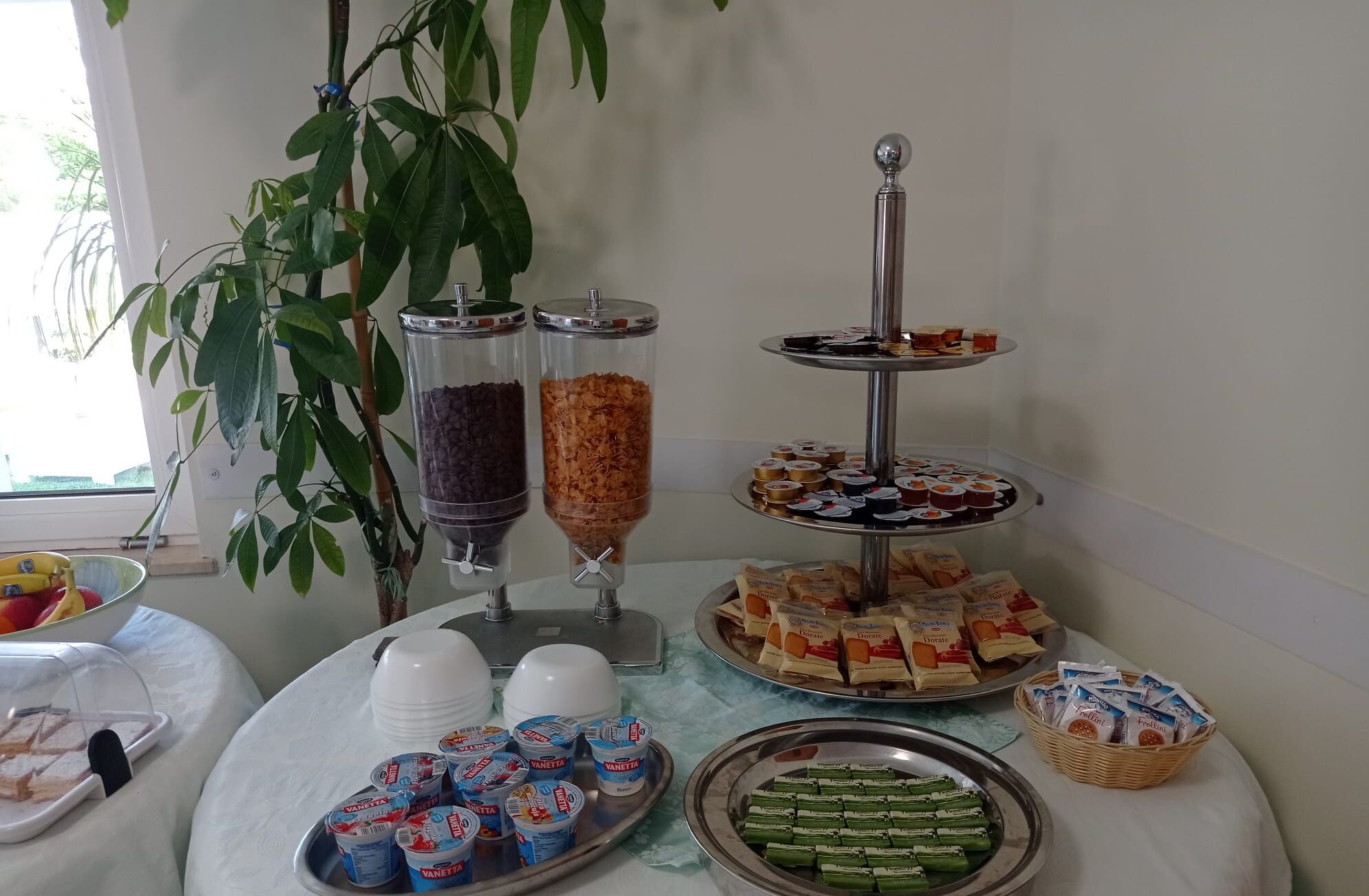 A buffet table with various food items, including trays of sandwiches, desserts, and packaged snacks.
